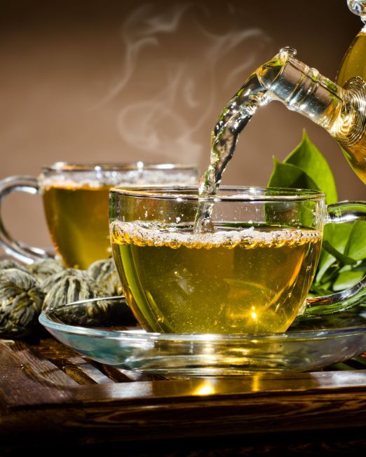 horizontal photo, of the glass teapot flow green tea in cup on brown background,  tea ceremony